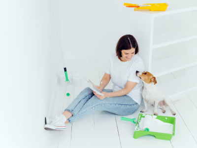 Woman and a small dog sitting on the bathroom floor in the middle of a do-it-yourself renovation. 