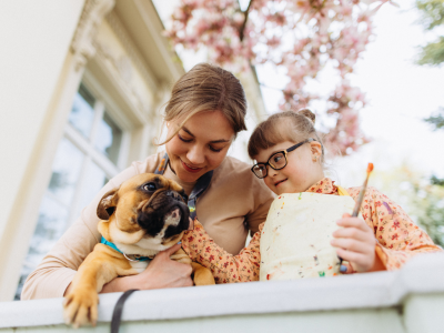 A woman and a girl with a mental disability outside with a therapy dog.