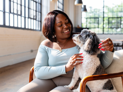A therapist and a gray and white therapy dog sit together in a chair during an AAI session