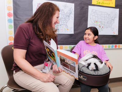A young girl holding a little guinea pig sits in her lap during a session.