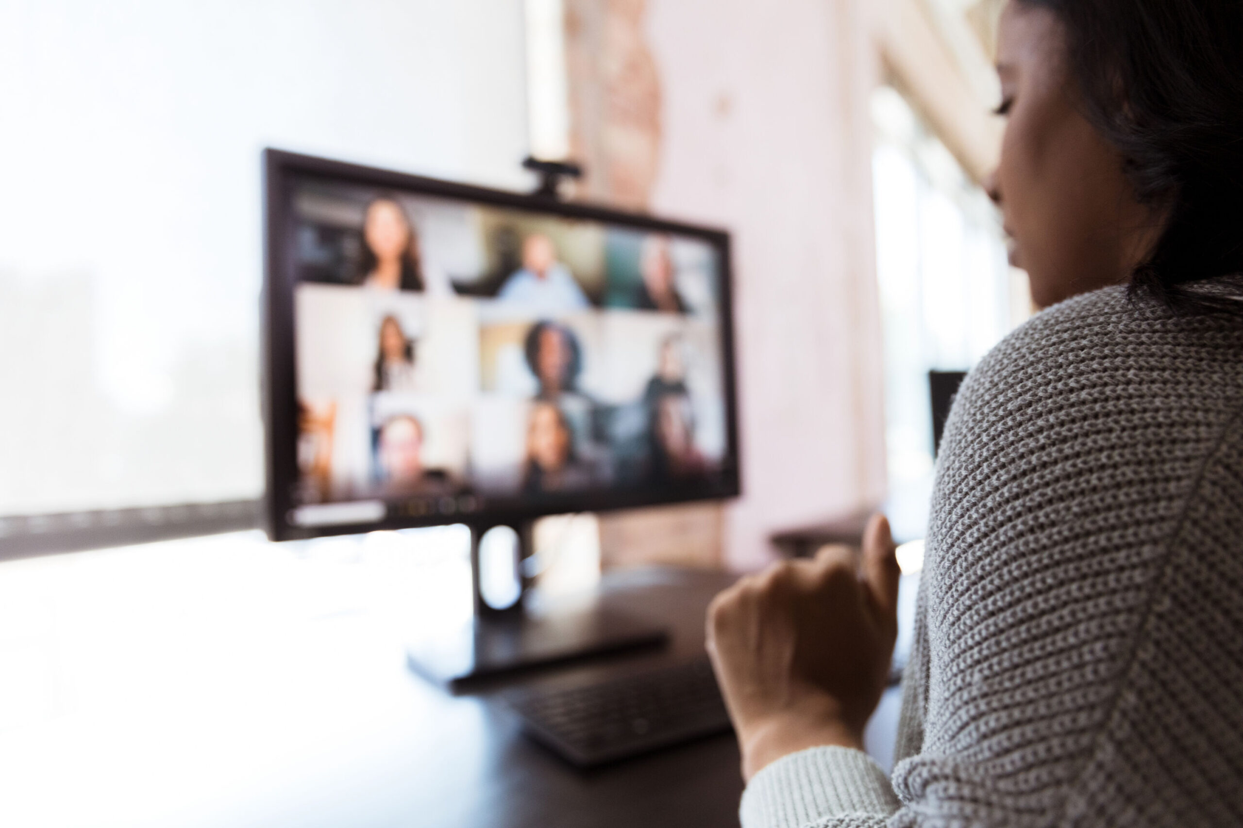 Young African-American woman in front of a desktop with people on a conference call at an event.