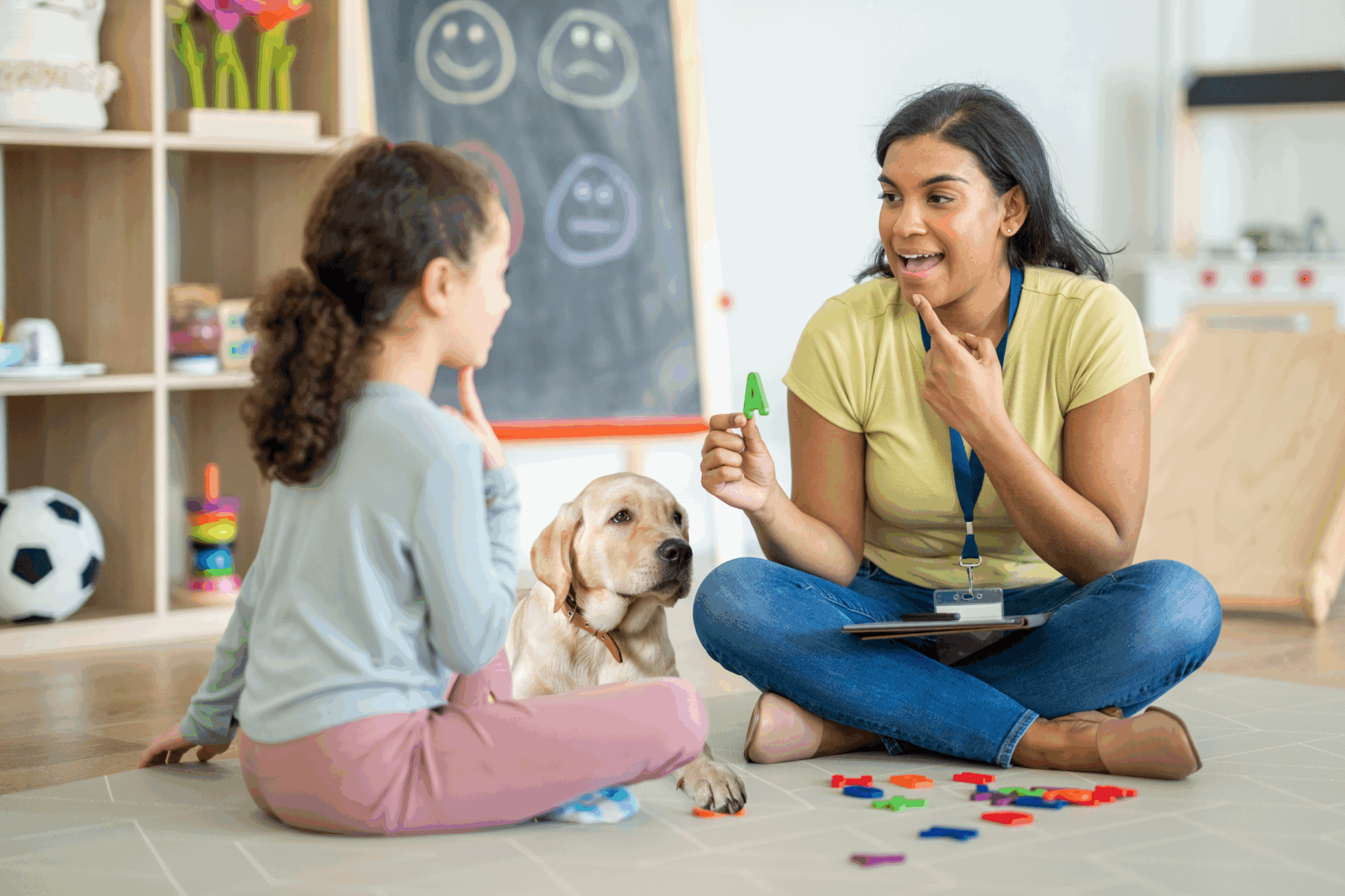 Speech-language pathologist practices letters with a child with help of therapy animal