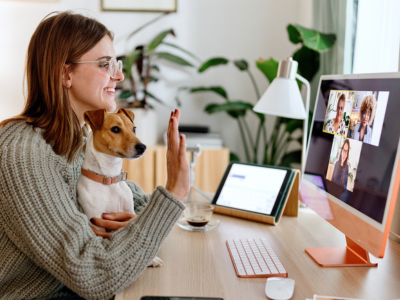 AAI professional at a computer with a dog on her lap greets other professionals through video conferencing