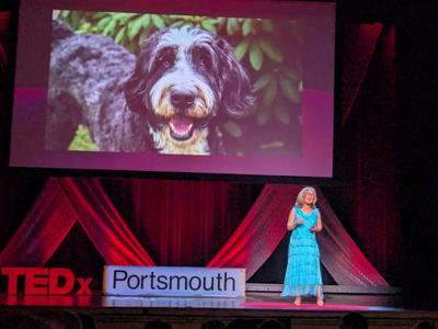 Woman stands on stage and gives TED presentation about therapy animals